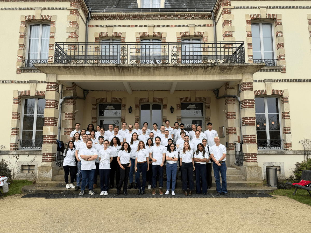 Around 40 members of the Greensolver team standing in front of the Château de Mée, all wearing white polo shirts