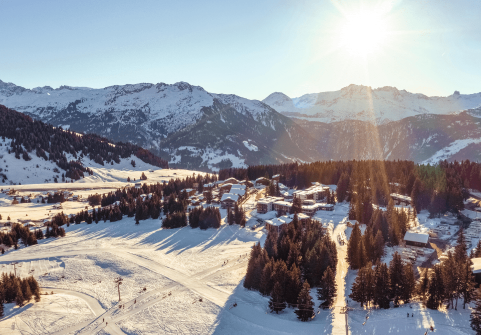 Vue aérienne d'une station de ski avec des montagnes enneigées au lever du soleil.