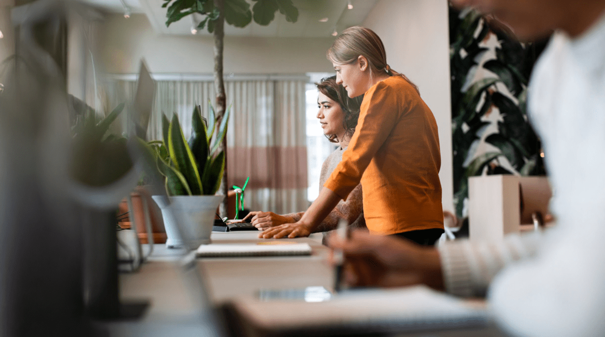 Two women standing beside each other, looking at a screen