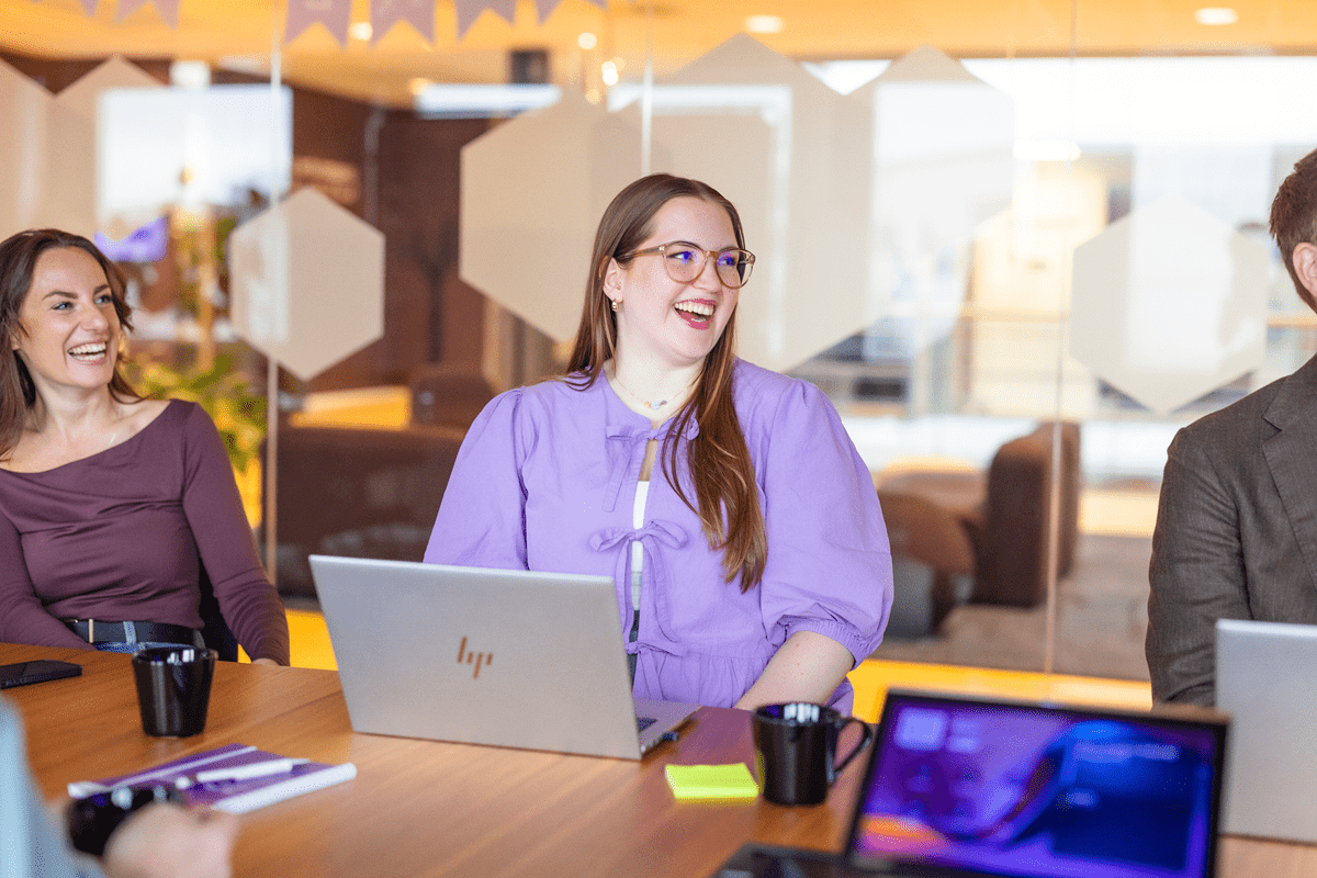 Två kvinnor skrattar vid dator i kontor.