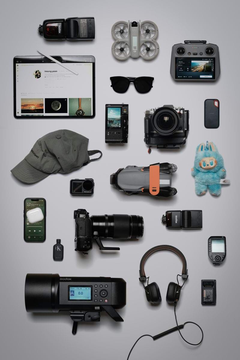 Flat lay of photography and tech gadgets on a grey background.