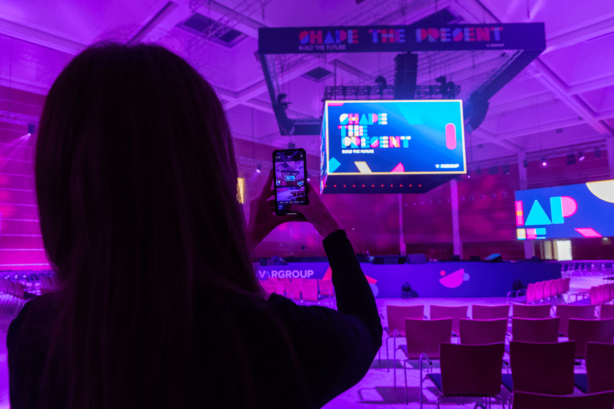 L'immagine ritrae una ragazza che scatta una foto all'interno dell'evento Var Group Shape the present del 2023