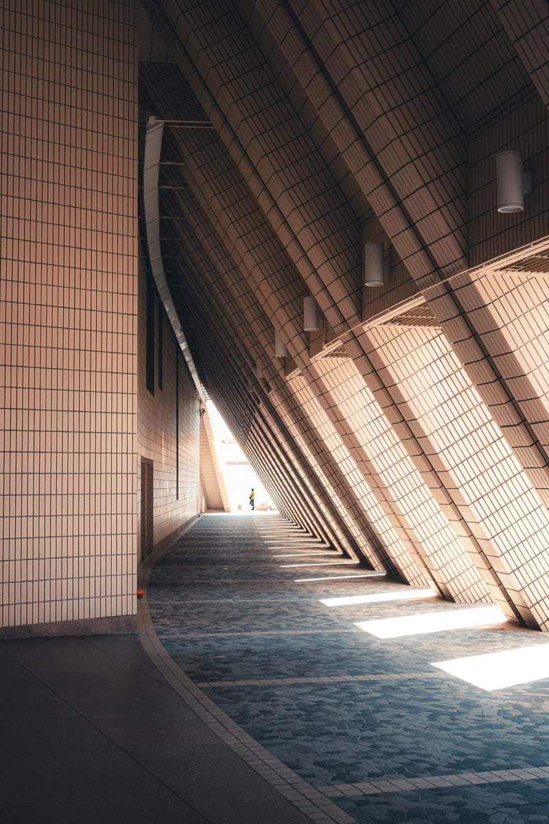 Modern architectural walkway with angled roof and sunlight.