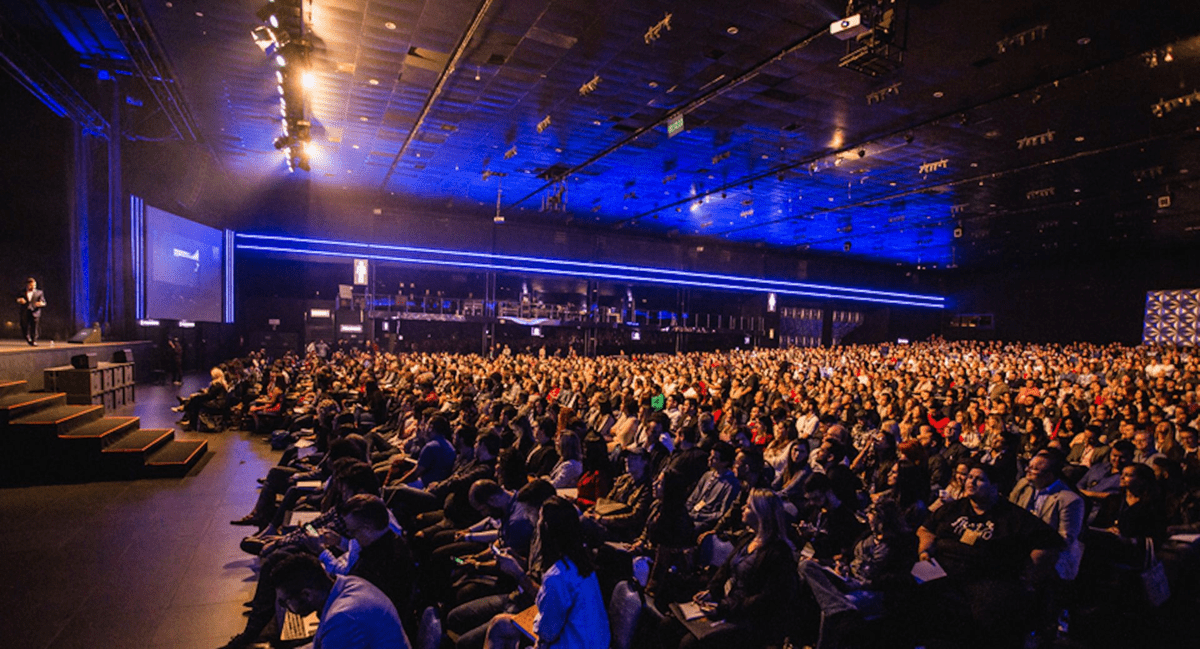 A speaker on stage at a large auditorium event