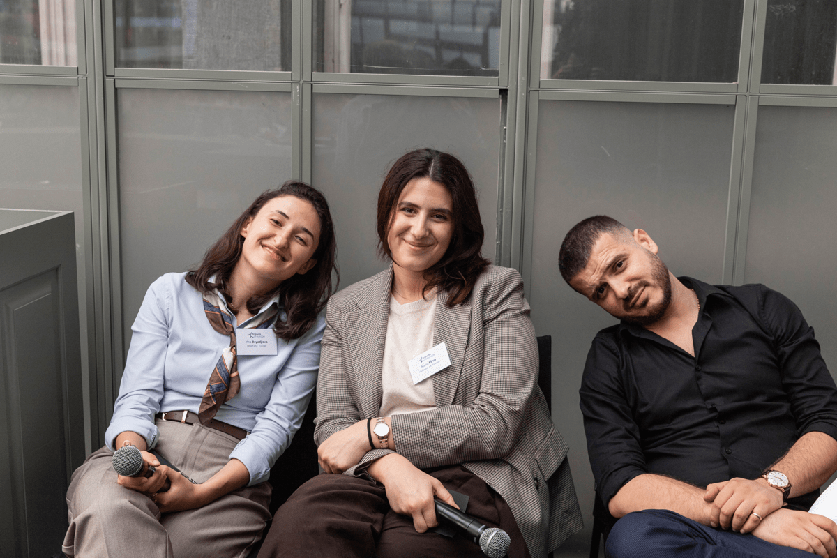 Three colleagues sitting together, smiling at the camera