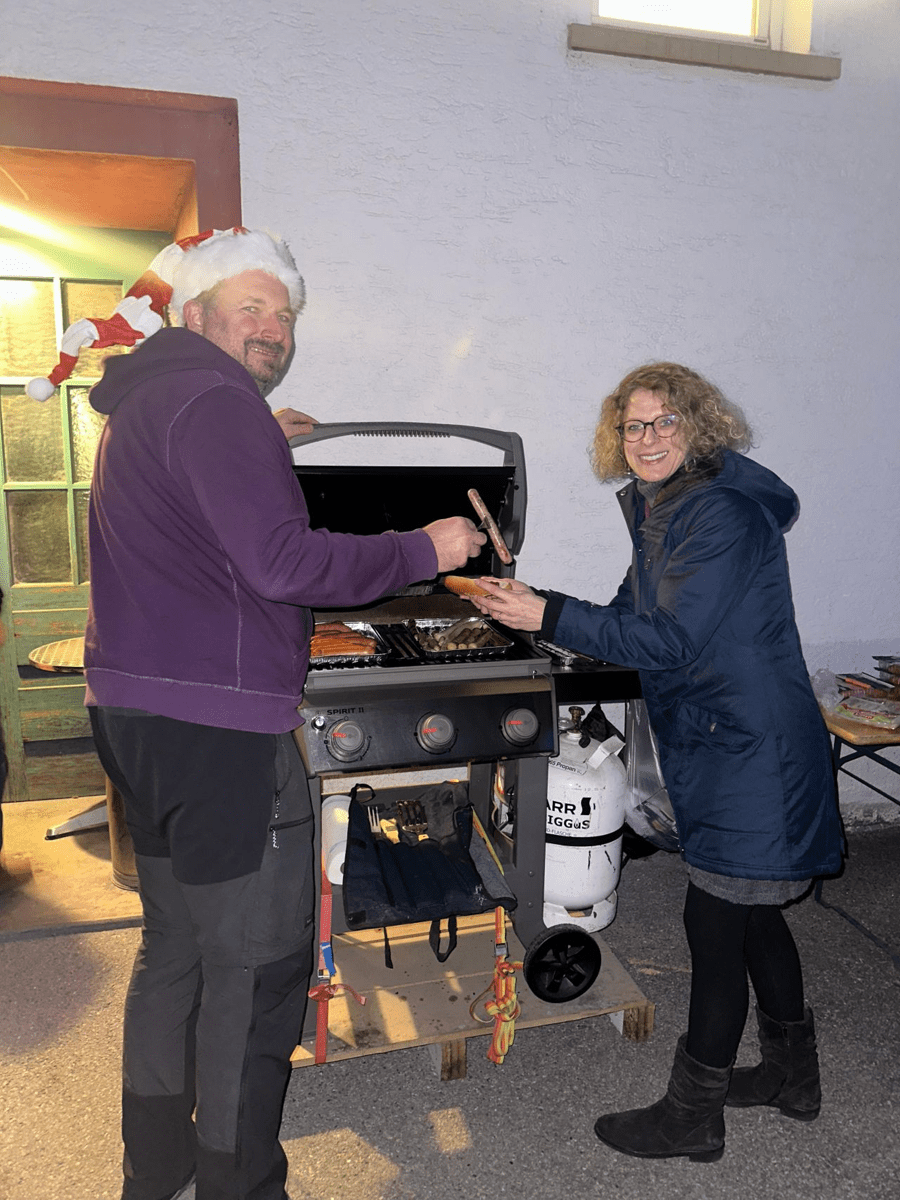 Ein Mann und eine Frau Grillen, der Mann steht links und trägt eine Nikolausmütze