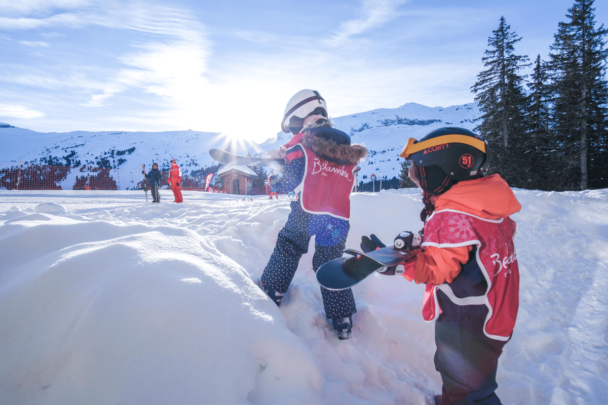 Enfants jouant dans la neige, sous la supervision d'un moniteur de ski Belambra.