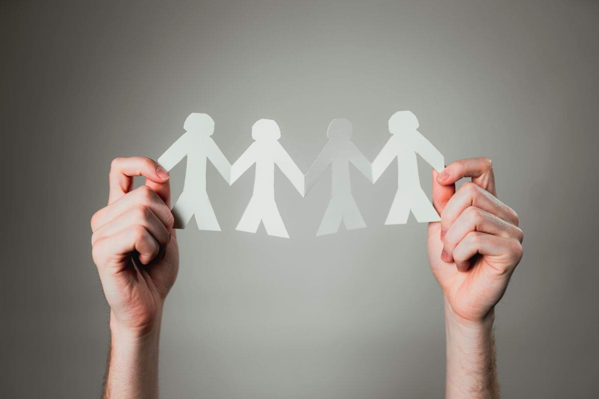 hands holding paper cutout family chain