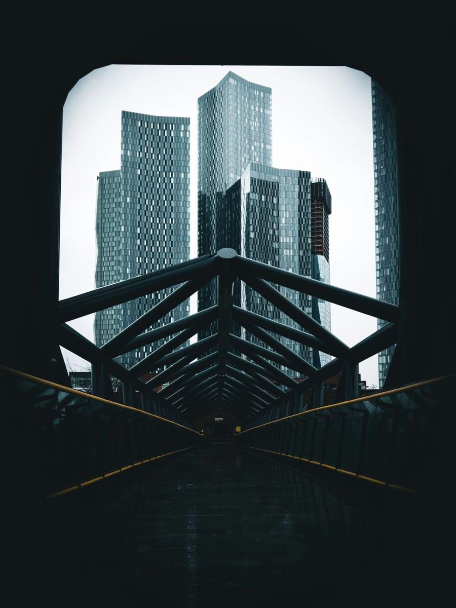 Modern skyscrapers seen through a dark tunnel structure.