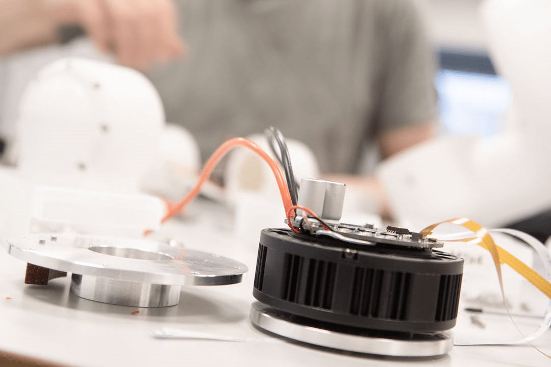 Electronics from inside DXT are spread out on a table. An engineer is working at the table.