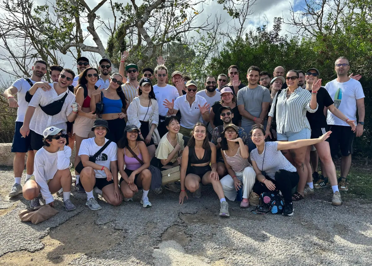 A large group of colleagues posing together outdoors during a team event.