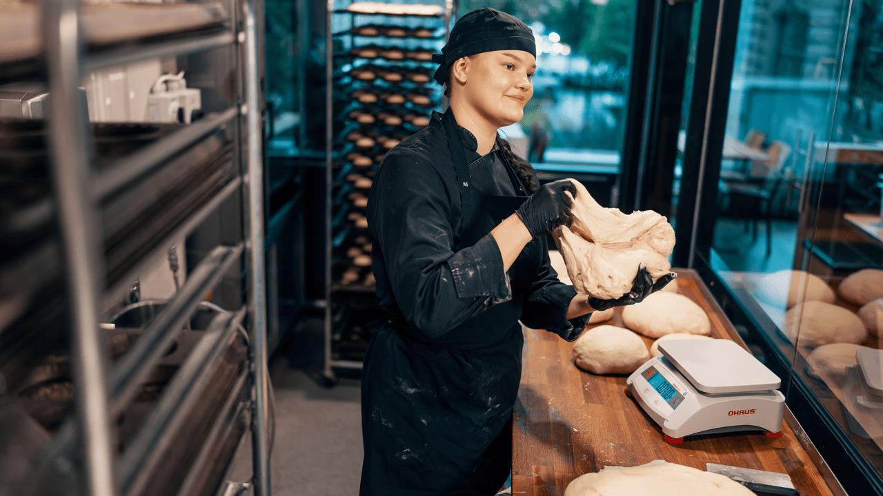 Työntekijä leipoo sämpylätaikinaa