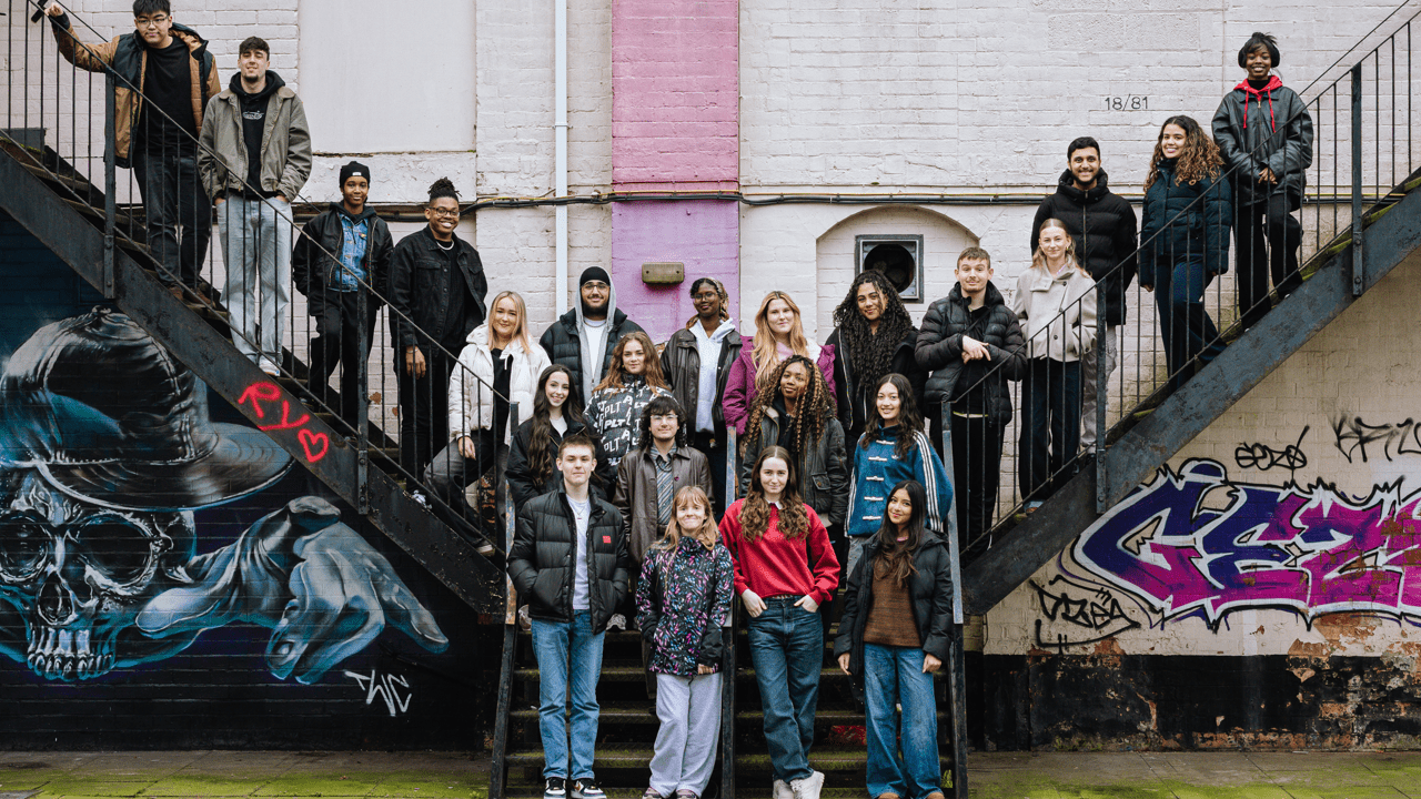 Young advocates group stand together on a staircase that features two staircases on opposite sides, that then feed into a singular staircase.