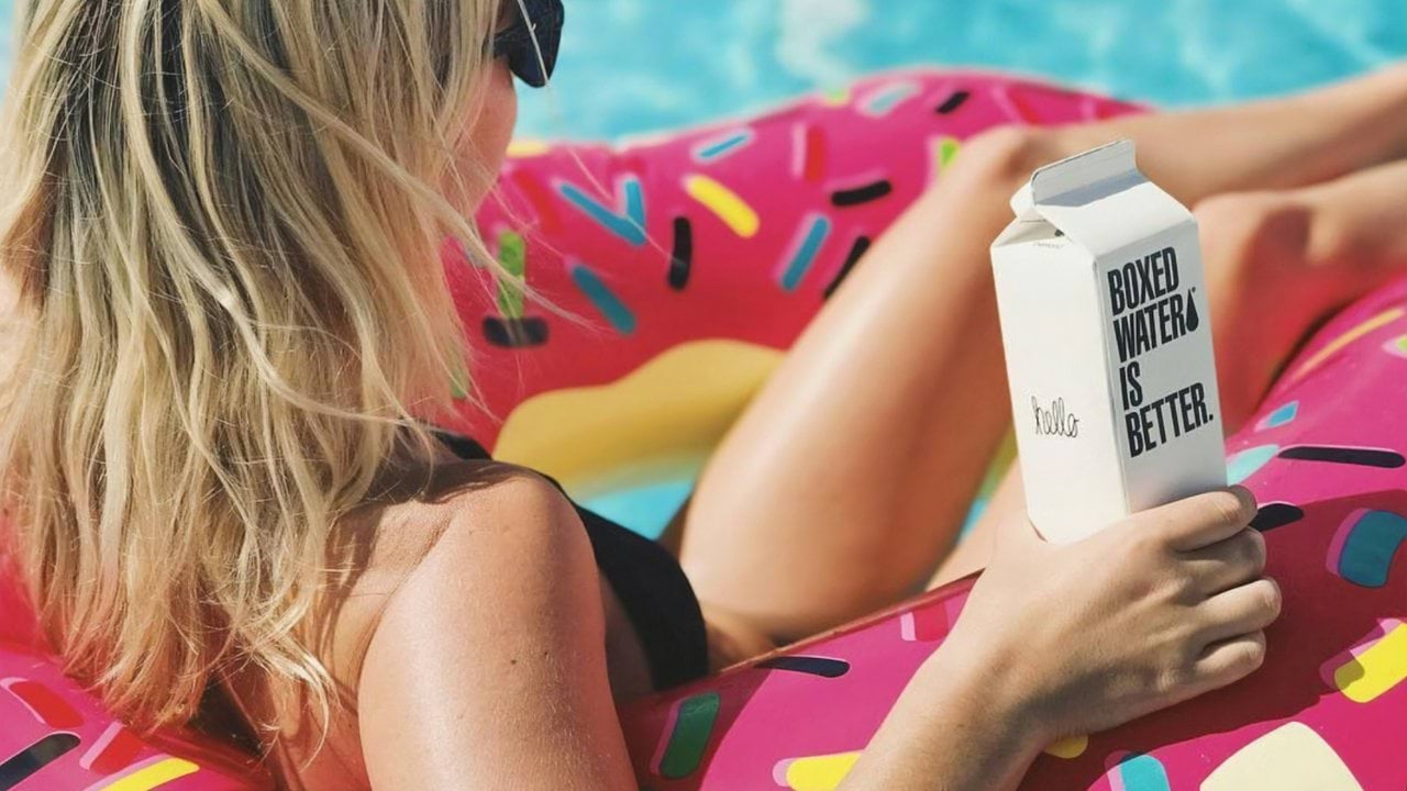 four women holding drinks while laughing together during daytime
