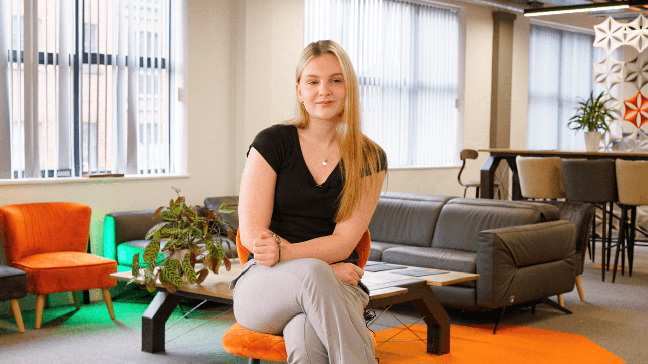 A woman sat on a chair in an office looking at the camera