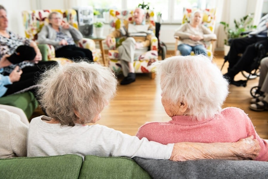 Ett tiotal kunder sitter samlade i en ring, i ett sällskapsrum på ett av Attendos särskilda boenden.