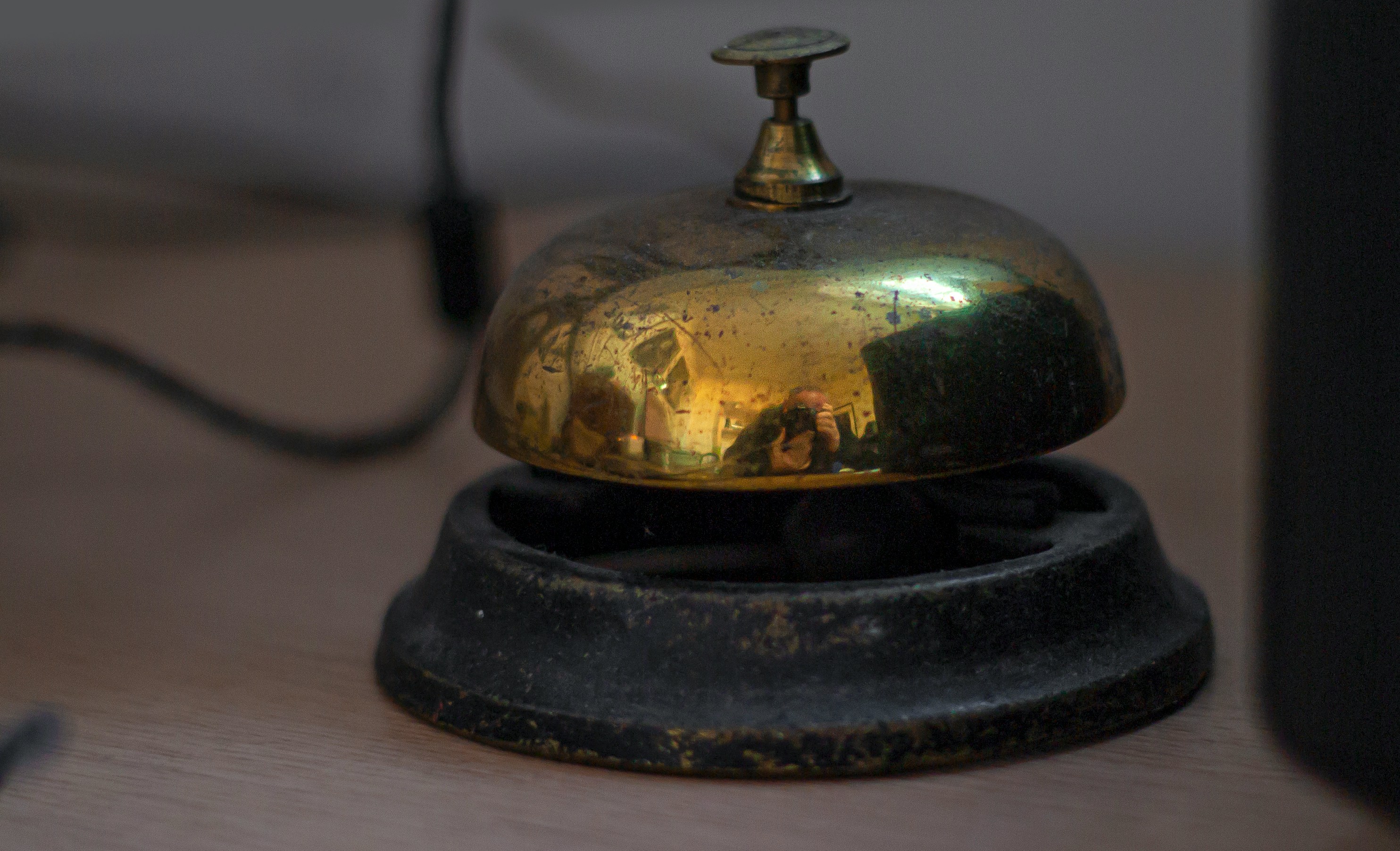 A vintage brass service bell on a wooden desk