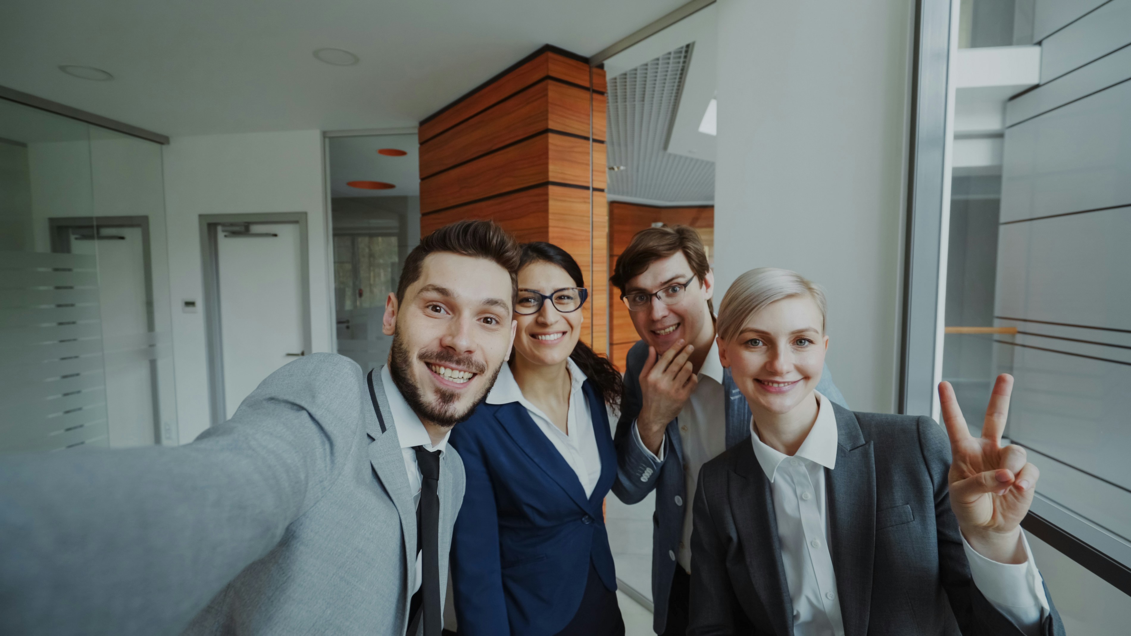Four business people taking a selfie in an office.