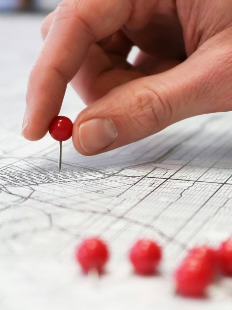 person placing red pin on city map