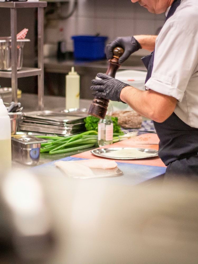 man putting herb on food