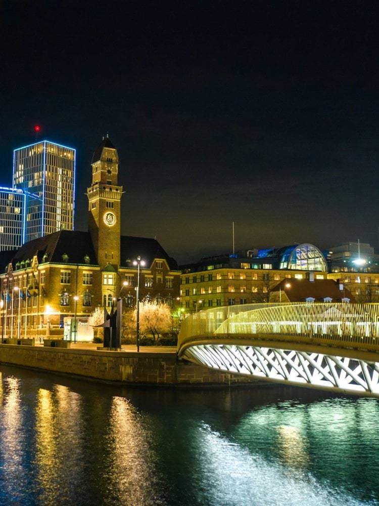 lighted bridge near city buildings during night time