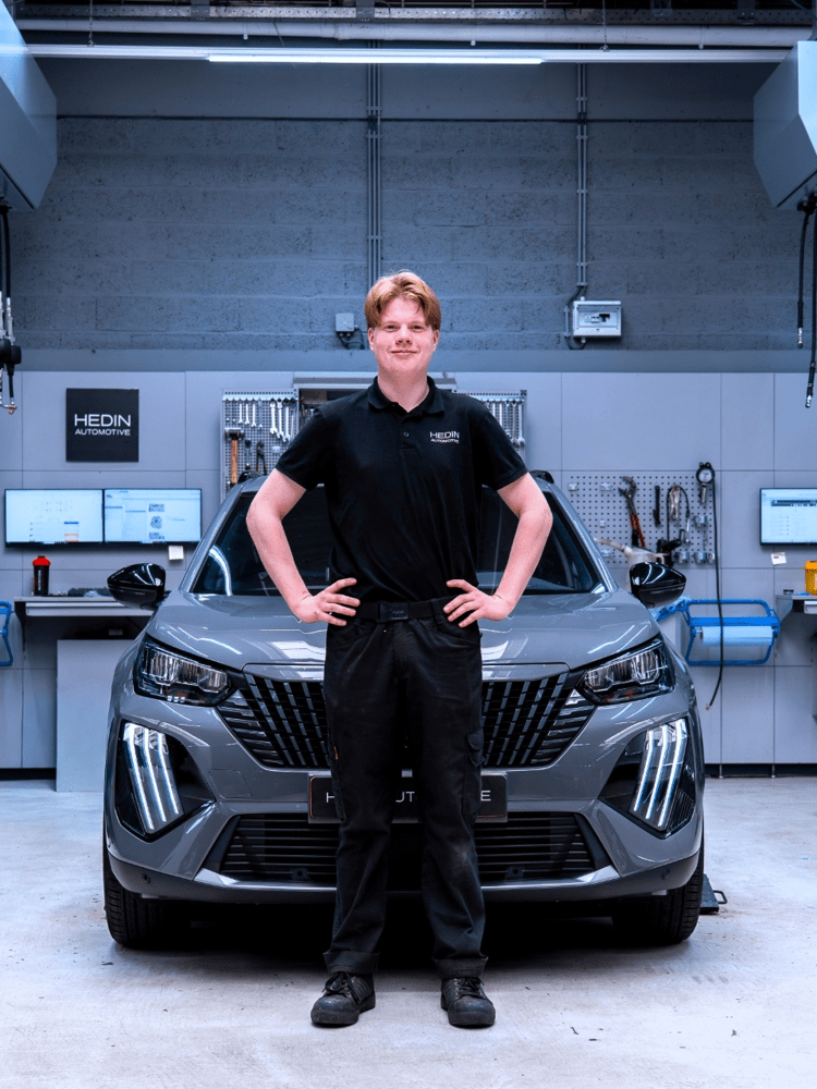 Leerling automonteur bij auto op brug in werkplaats - autotechniek