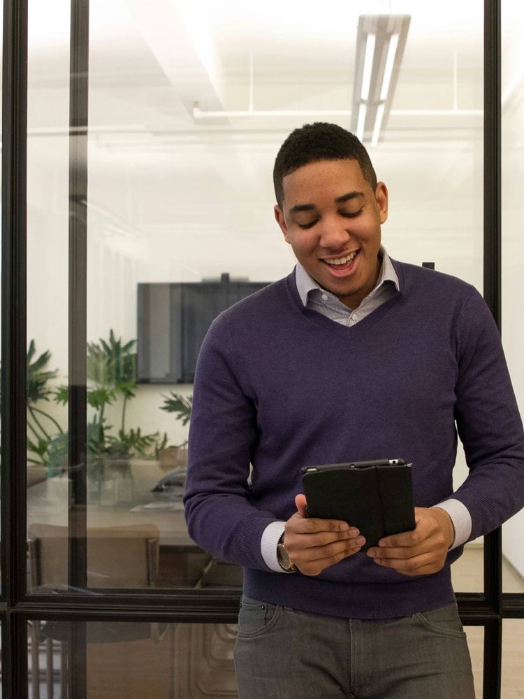 a man standing in an office looking at a tablet