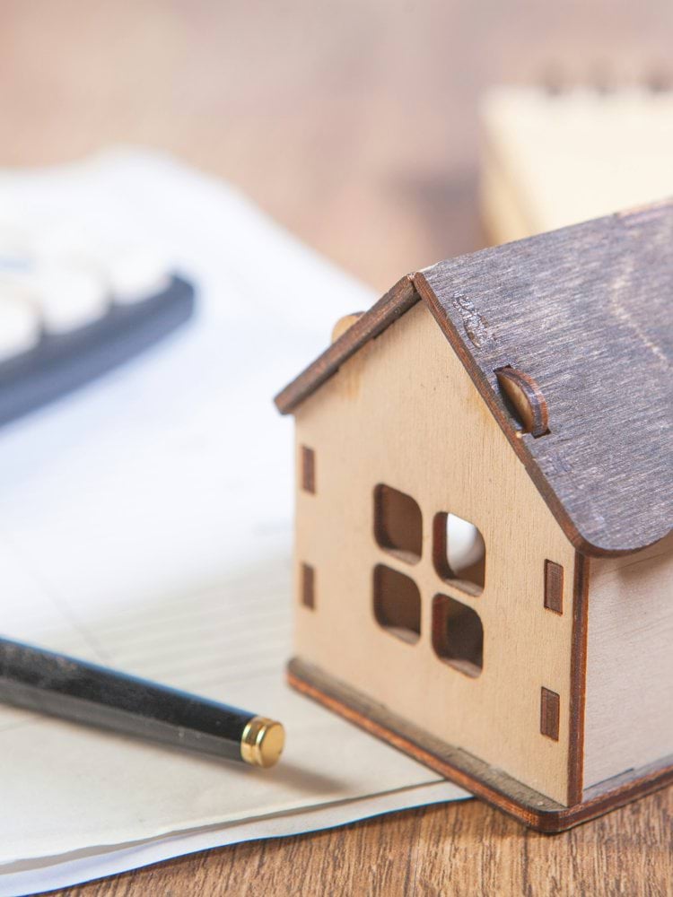 Model house with calculator and pen on desk