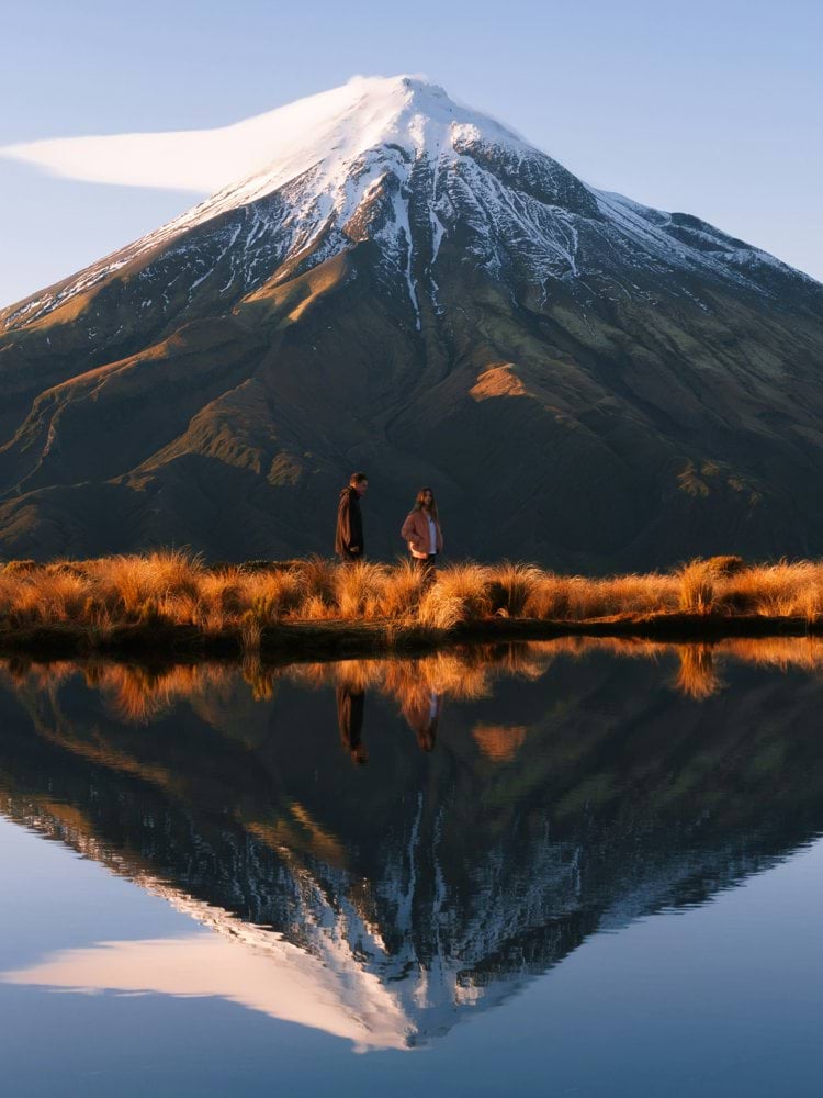 a man and a woman standing in front of a mountain