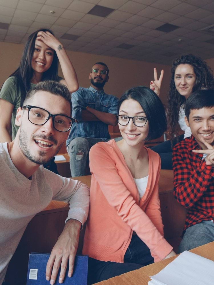 Group of smiling students taking a selfie in classroom