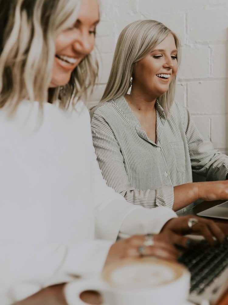 two women using laptops