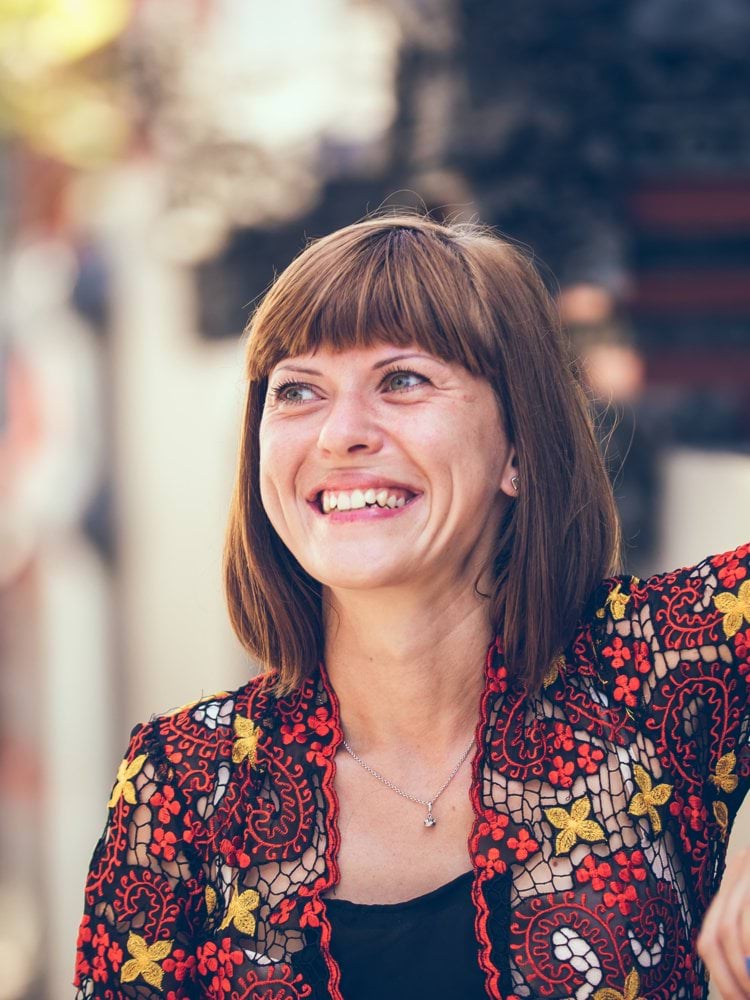 woman in floral-themed cardigan leaning on fence in bokeh photography