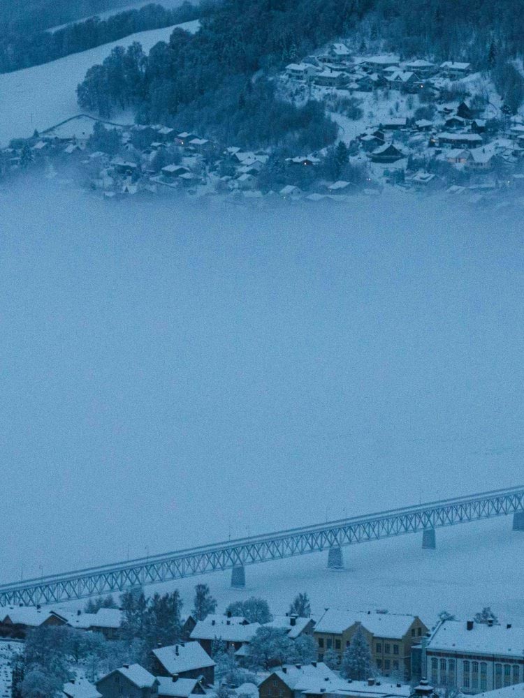 a snowy town with a bridge and a bridge in the background