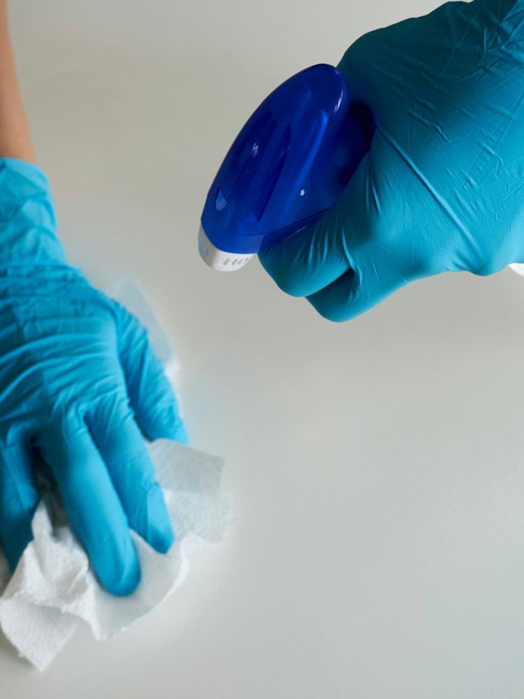 person in blue gloves holding white textile