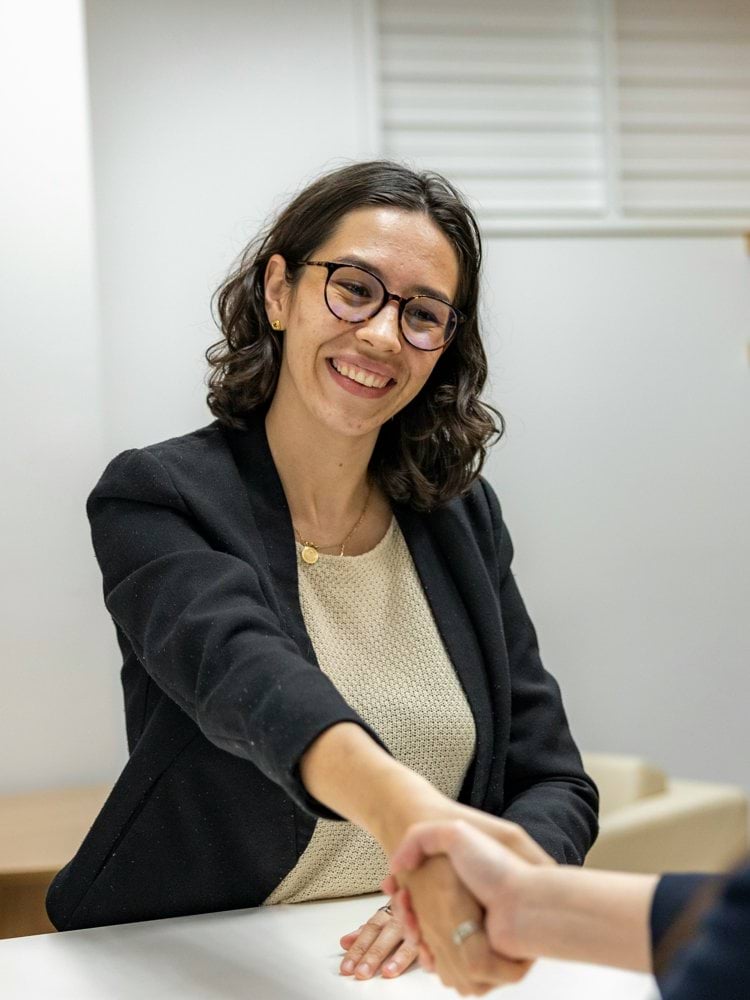 a woman shaking hands with another woman sitting at a table