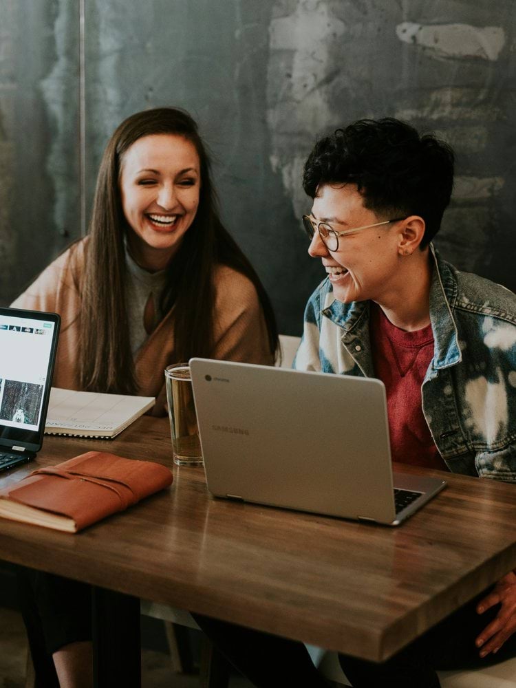 three people sitting in front of table laughing together