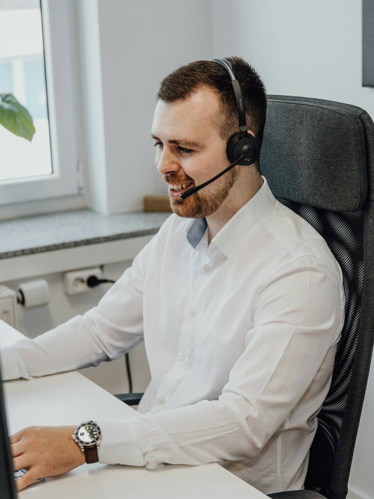 a man wearing a headset sitting in front of a computer