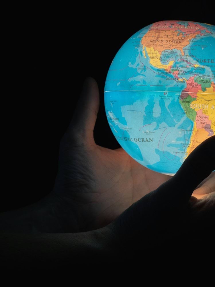 blue and brown globe on persons hand