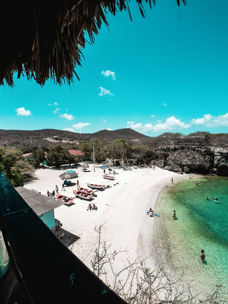a beach with people on the sand and clear water