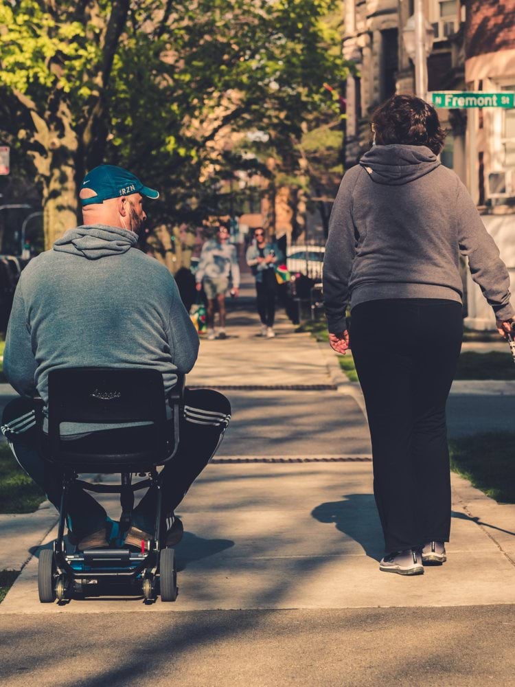 man in gray hoodie and black pants sitting on black and gray stroller during daytime