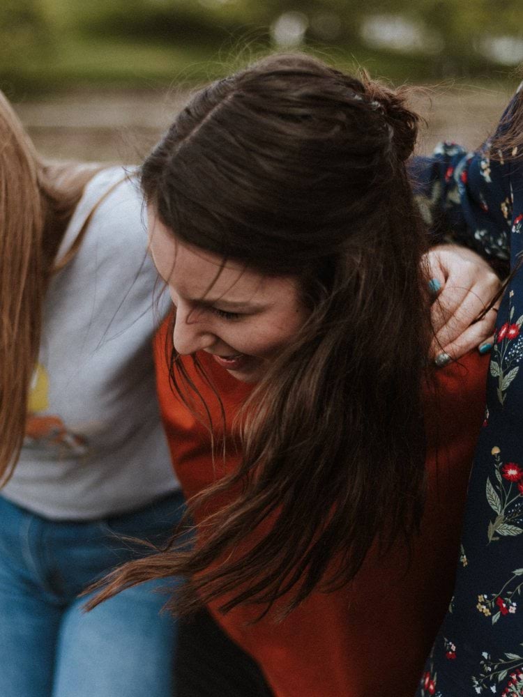 three woman holding each other and smiling while taking a photo
