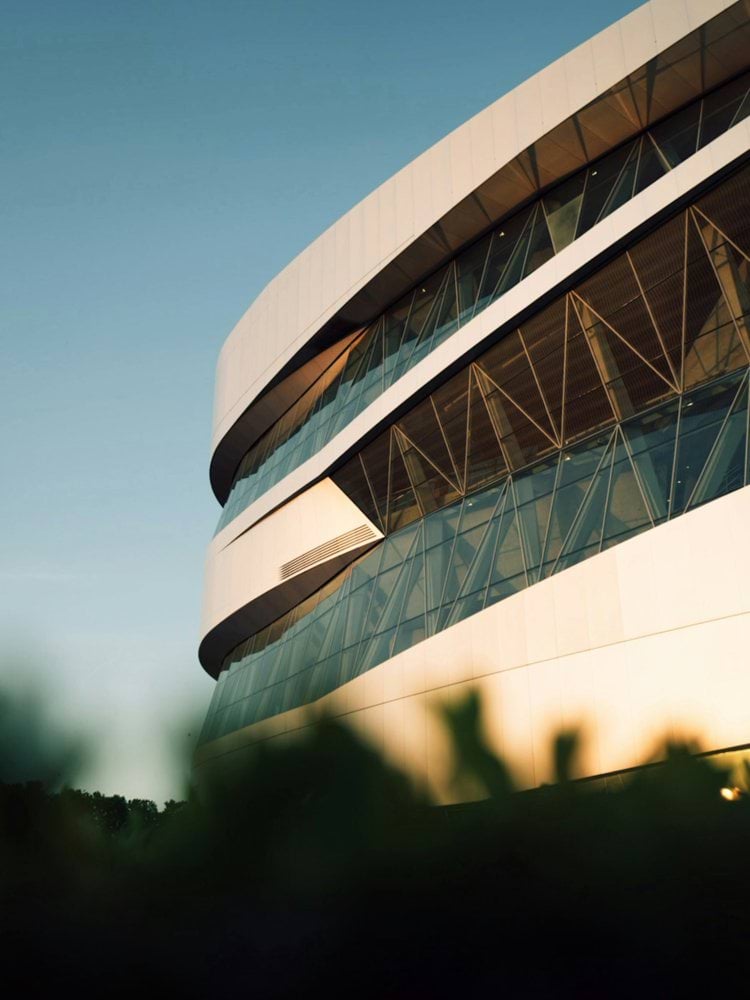 Modern curved white building with geometric windows under blue sky.