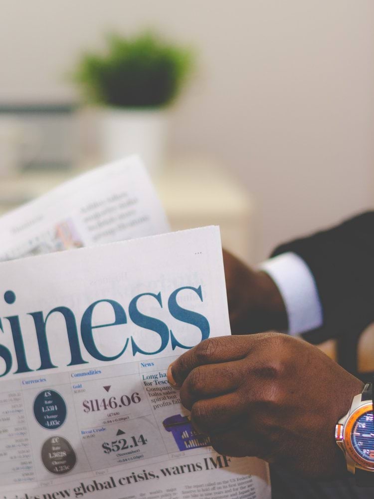 person wearing suit reading business newspaper