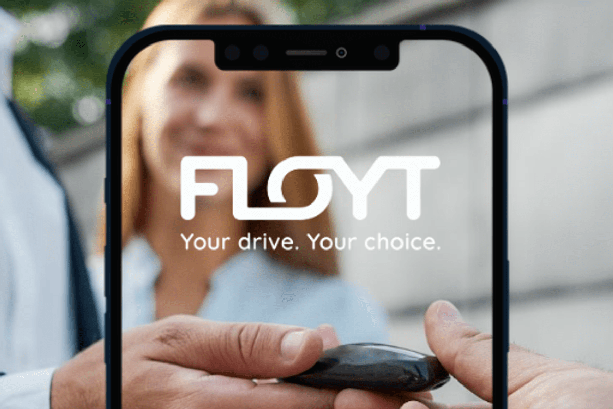 Person handing over car keys framed by a smartphone mockup displaying the FLOYT logo and tagline 'Your drive. Your choice.