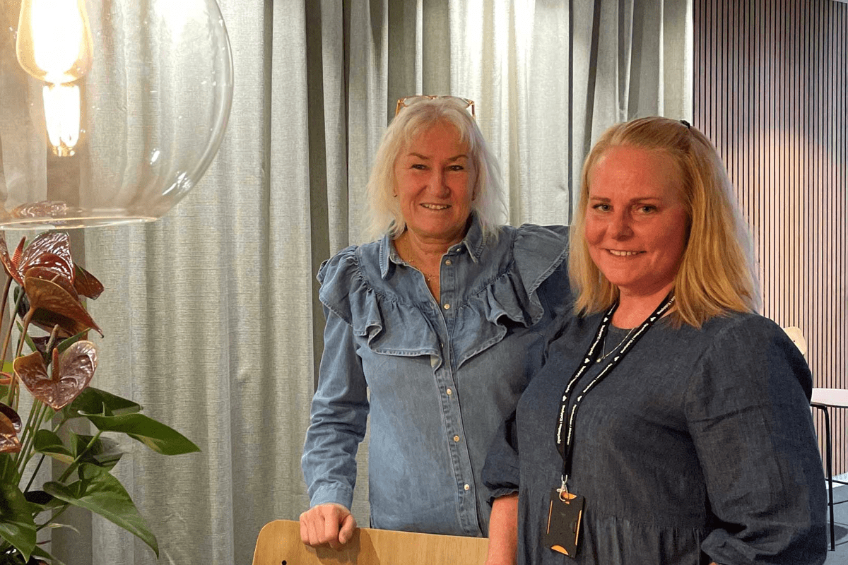 två kvinnor står intill en blomma