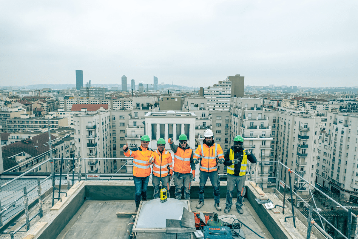 Équipe de chantier Carrion TP sur un toit-terrasse avec vue panoramique sur la ville.