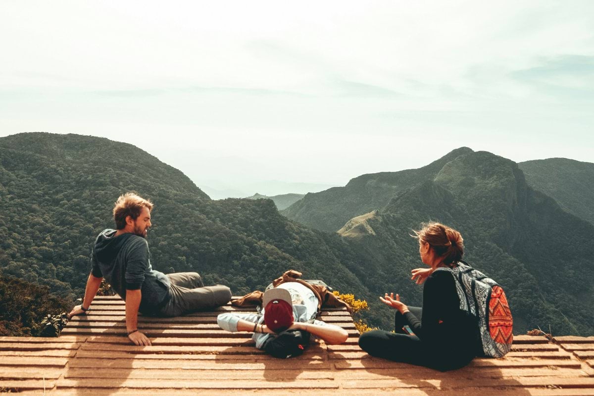three people overlooking mountains