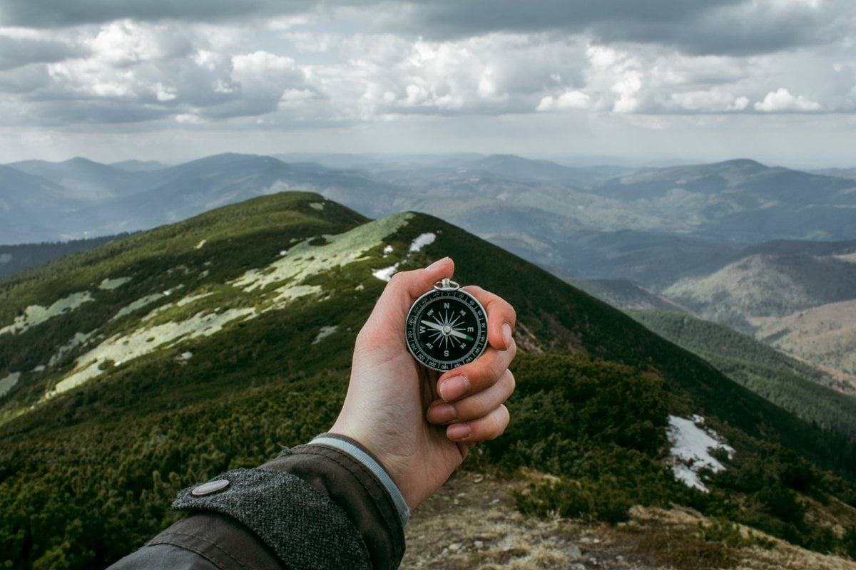 person holding silver compass