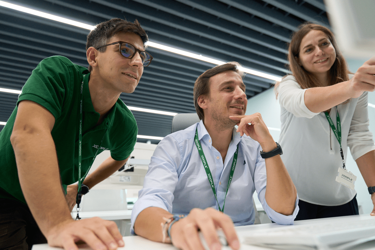 Two male, and one female colleague, review work on a computer screen