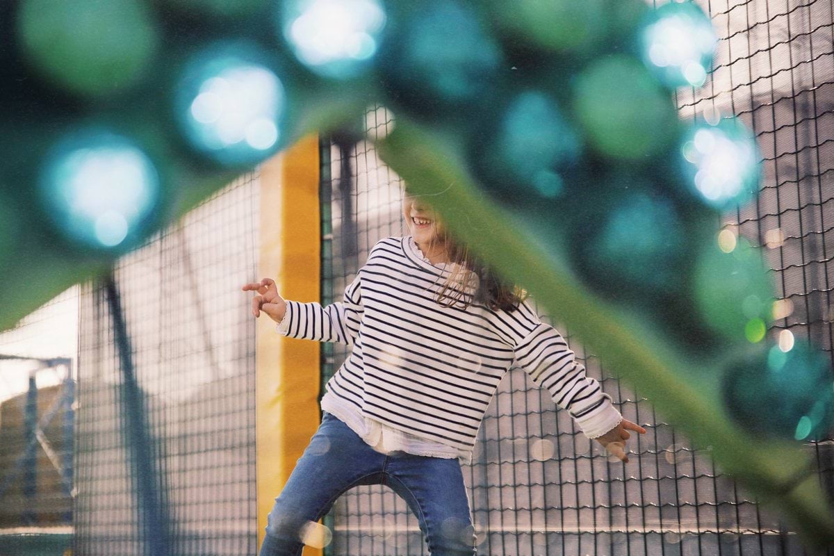 girl wearing white and black striped long-sleeved shirt playing in playground during daytime